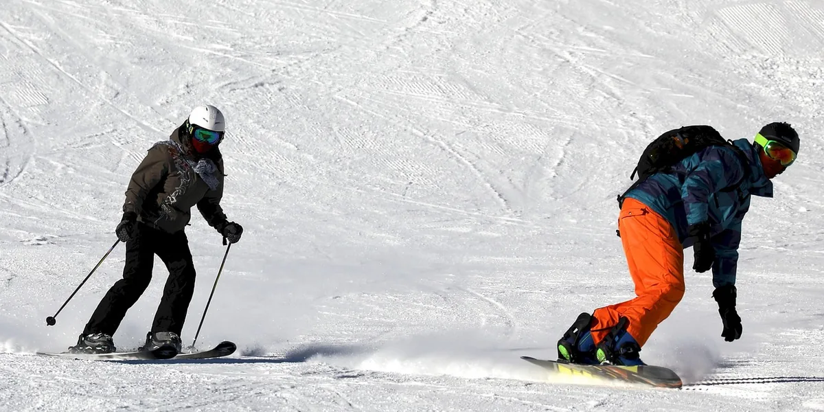 Narciarz i snowboardzista zjeżdżają obok siebie po stoku