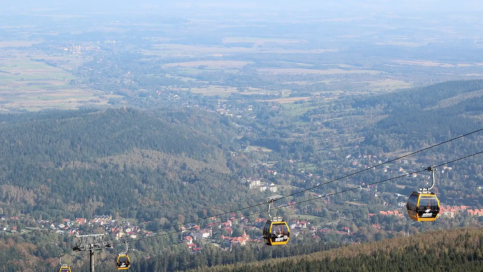 Gondole kolei na Stóg Izerski nad zalesionym zboczem, w dole Świeradów-Zdrój, zdjęcie latem