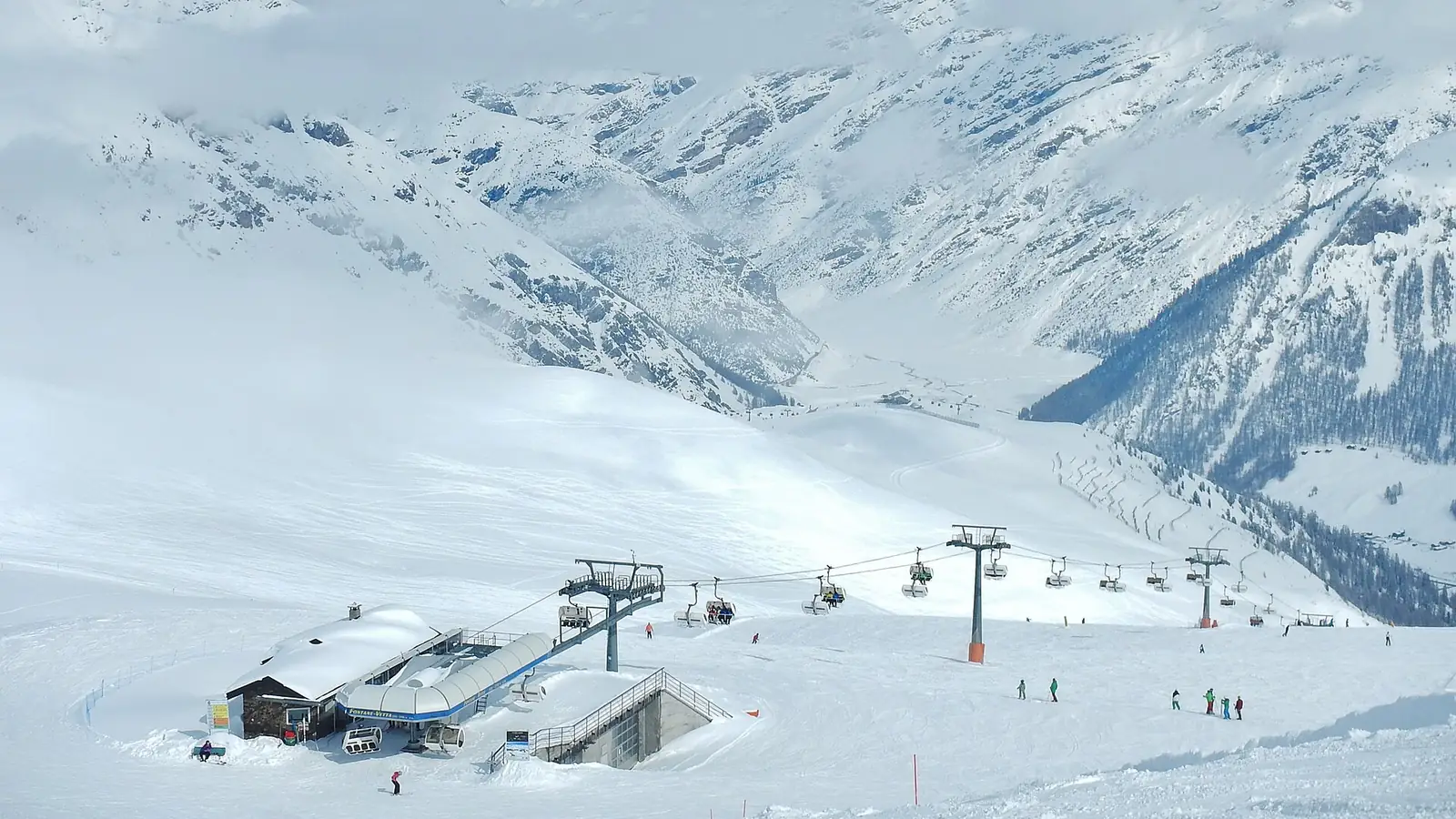Ośnieżone stoki ośrodka Livigno z kolejami krzesełkowymi i stacją wyciągu Costaccia