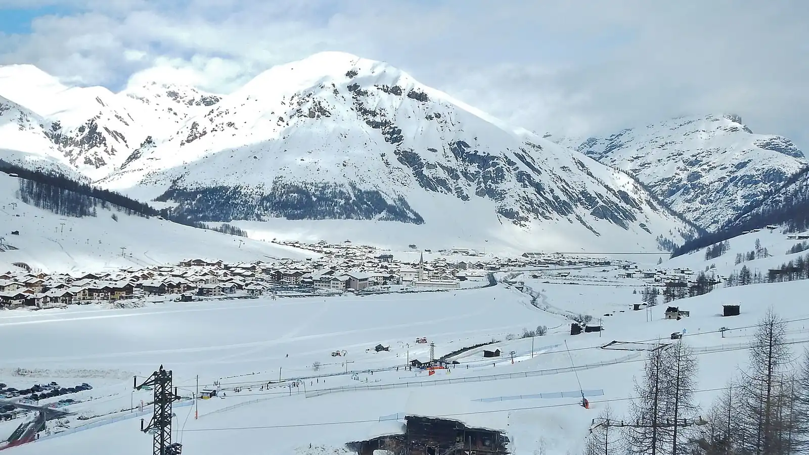 Ośnieżona dolina z zabudową Livigno u stóp zaśnieżonych szczytów, widok ze stoków Mottolino